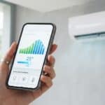 A homeowner using a smartphone application to monitor and track real-time aircon energy consumption and adjust temperatures in a Singapore apartment.
